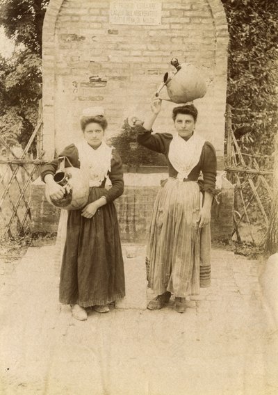 Geleneksel kıyafetler giyen ve kuyu başında pişmiş toprak küpler taşıyan iki genç kadın, Marche, İtalya, 1910 civarı by Italian Photographer