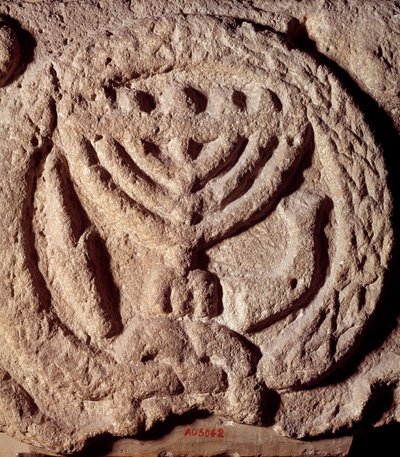 Yahudilik: yedi dallı (Menora veya Menora), palmiye ve trompetli bir şamdanla süslenmiş bir sinagogun bazaltındaki mimari unsur. Transjordan