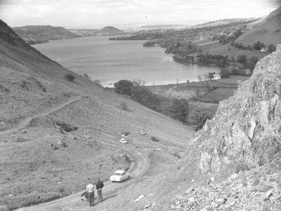 Yol, arabalar ve insanlar, arka planda göl ile bir yamaçtan aşağıya bakan bir manzara by Joseph Hardman