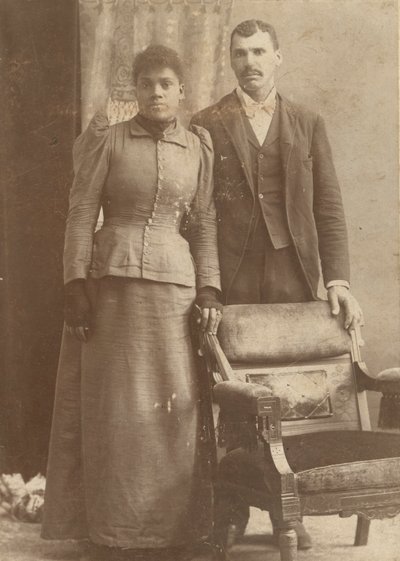 Bir sandalyenin arkasında duran Afrikalı-Amerikalı bir çiftin fotoğrafı, yaklaşık. 1890. by Schmitz Studio