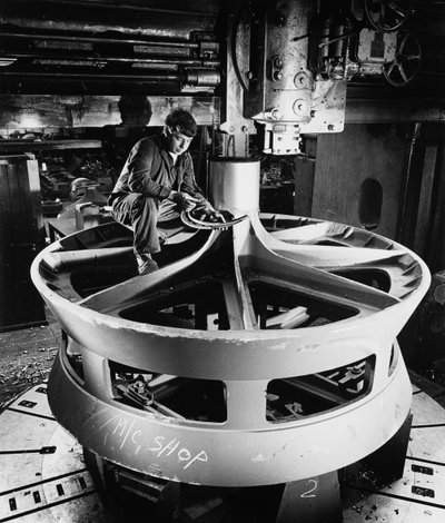 Büyük bir döküm parçanın üstündeki tesisatçı dikey delme makinesi kullanıyor by Unbekannt