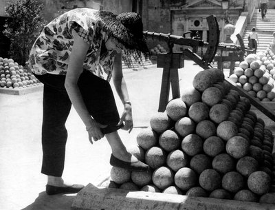 Bir kadın, Roma#39;daki Castel Sant#39;Angelo arazisindeki gülle yığınının üzerine ayağını koyarken pantolonunun manşetini düzeltiyor. by Unknown photographer
