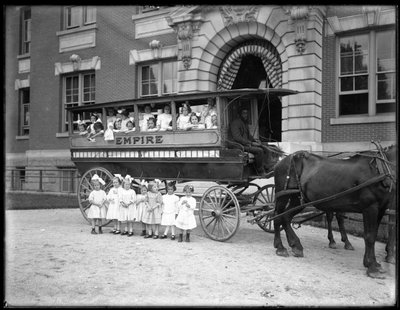Küçük kızlar atlı bir vagonun içinde ve önünde, kimliği belirsiz bir binanın önünde poz veriyor, muhtemelen Roma Katolik Yetimhanesi, Kingsbridge, Bronx, 1910 dolayları by William Davis Hassler